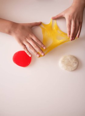 Işığın altında yumuşak, parlak balçık geren eller. Renk, doku ve hayal gücünü ifade eder.