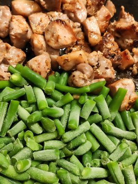 Taze fasulye ve tavada cızırdayan kızarmış et. Sıcak, kırsal bir yemek, zengin dokular ve taze malzemelerle..