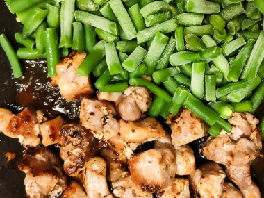 Taze fasulye ve tavada cızırdayan kızarmış et. Sıcak, kırsal bir yemek, zengin dokular ve taze malzemelerle..