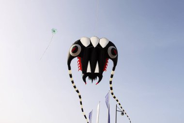 Renkli bir uçurtma parkın üzerinde uçar. Özgürlük ve açık hava eğlencesi.