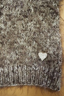 El yapımı gri örülü köpek süveteri, parlak kalp aksesuarları, yumuşak kabarık dokusu ve hafif bir arka planda rahat bir kış tasarımı. en üstteki görünüm