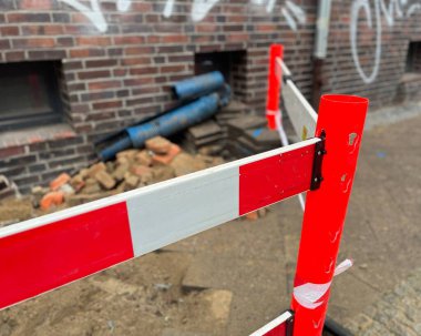 Szczecin, Polska 8 grudnia 2025: Avrupa 'nın Szczecin kentindeki turuncu ve beyaz plastik çitler tarafından korunan yol onarım ve kamu hizmetlerinin tipik kaldırım manzarası. Yazı