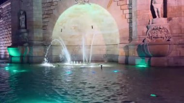 Geceleri, taştan çeşme suya yansıyan çok renkli kırmızı ve yeşil ışıklarla aydınlatılır ve gece şehrin detaylı heykelleri ve kemerli mimari tasarımı vurgulanır..