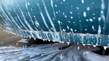 Araba yıkama sahnesi fırça temizleme bardağını köpük ve suyla gösteriyor. Otomobil yıkama, oto yıkama ve araç hijyen konsepti.