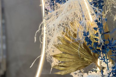 Kurumuş ortanca çiçekleri ve yumuşak dekoratif ışıklandırmayla aydınlatılan narin otlarla süslü zarif bir çiçek dikimi rüya gibi ve romantik bir atmosfer yaratıyor..