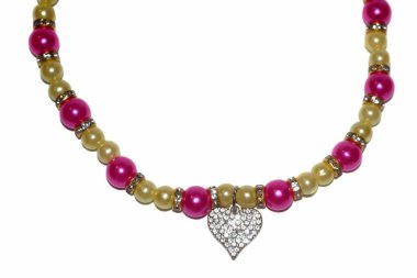 Parlak kalp kolyesi olan pembe ve sarı boncuklu bir köpek kolyesi beyaz arka plana yakın bir yerde yatıyor. Hayvan aksesuarları