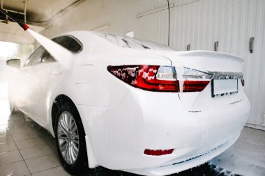 Araba yıkama. Araba Temizleme Suyu Kullanımı Yüksek Basınçlı Su. Erkek işçi arabayı yüksek basınçlı yıkama makinesiyle yıkıyor.