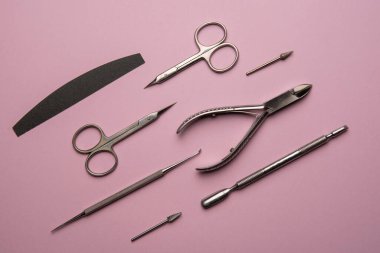 Pembe zemin üzerinde manikür aletleri ve aksesuarlar. Düz katman. Pembe arka planda manikür ve pedikür ekipmanlarının üst görünümü.