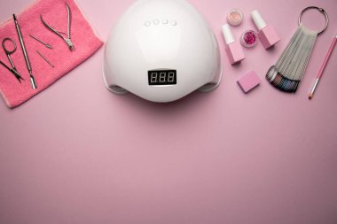 Pembe zemin üzerinde manikür aletleri ve aksesuarlar. Düz katman. Pembe arka planda manikür ve pedikür ekipmanlarının üst görünümü.