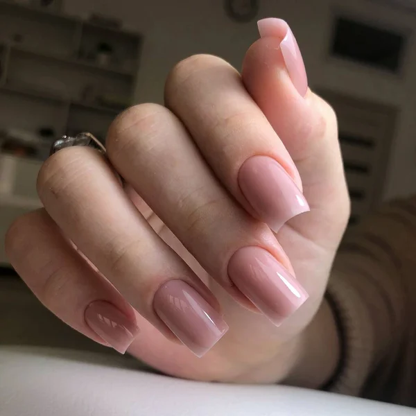 Tırnaklarında pembe manikür olan bir kadının elleri. Manikür güzellik salonu konsepti. Metin veya logo için boş yer.