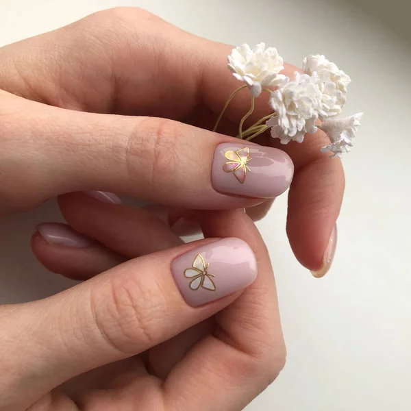 Pink manicure.Hands of a woman with pink manicure on nails.Manicure beauty salon concept. Pink manicure with butterfly design