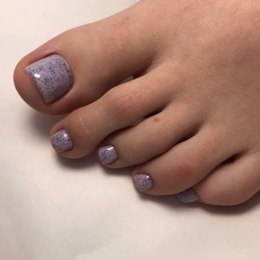 Mavi pedikür. Kadın ayaklarında mavi pedikür. Beyaz arka planda mavi pedikürlü kadın ayakları.