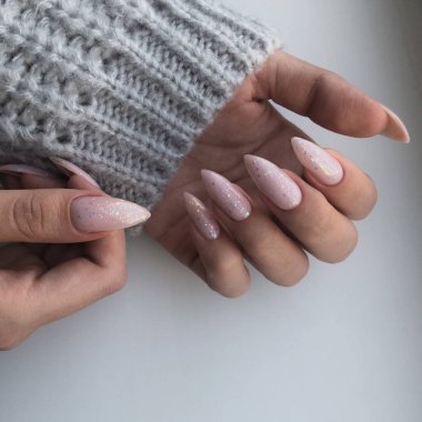 Tırnaklarında pembe manikür olan bir kadının elleri. Manikür güzellik salonu konsepti. Metin veya logo için boş yer.