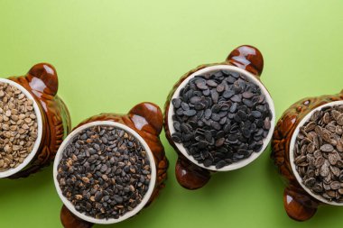 Yeşil arka planda kil kaplarda farklı çeşitteki karpuz tohumları. Karpuz tohumları arka planda.