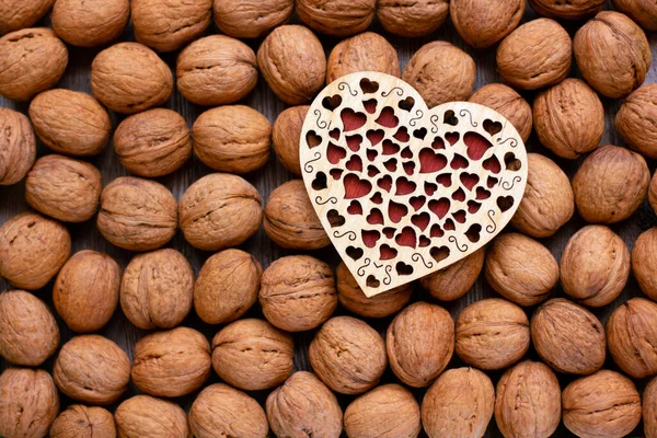 Walnut kernels and a wooden heart. Healthy nutrition concept. Nature background. Flat lay.