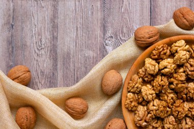 Ahşap bir tabakta ceviz çekirdekleri olan ve kumaşla süslenmiş modaya uygun bir düzen. Sağlıklı beslenme konsepti. Doğa geçmişi. Düz yat, boşluğu kopyala.