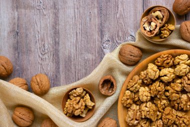 Ahşap bir tabakta ceviz çekirdekleri olan ve kumaşla süslenmiş modaya uygun bir düzen. Sağlıklı beslenme konsepti. Doğa geçmişi. Düz yat, boşluğu kopyala.