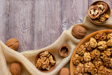 Ahşap bir tabakta ceviz çekirdekleri olan ve kumaşla süslenmiş modaya uygun bir düzen. Sağlıklı beslenme konsepti. Doğa geçmişi. Düz yat, boşluğu kopyala.