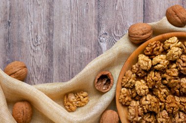 Ahşap bir tabakta ceviz çekirdekleri olan ve kumaşla süslenmiş modaya uygun bir düzen. Sağlıklı beslenme konsepti. Doğa geçmişi. Düz yat, boşluğu kopyala.