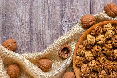 Ahşap bir tabakta ceviz çekirdeklerinin yaratıcı düzeni ve kumaşla süslenmiş. Sağlıklı bir yaşam tarzı. Beslenme konsepti. Düz yat, boşluğu kopyala.