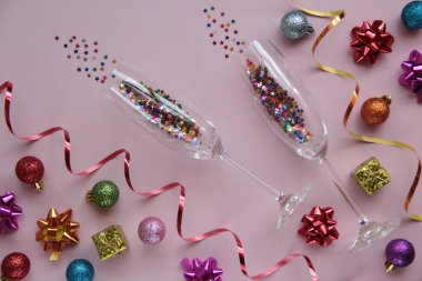 Pembe arka planda gözlük ve şenlik dekorasyonları olan modaya uygun bir yer. Yılbaşı ve parti konseptlerini kutlamak. Tebrik kartı. Düz arkaplan.