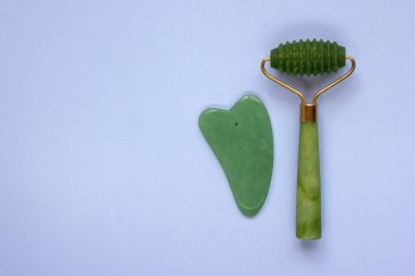 Jade Face Roller ve Gua sha Stone güzellik masajı terapisi için. Cilt Bakımı Yaşlanma Karşıtı Aracı. Doğal bütünsel güzellik kavramı. Düz yat, boşluğu kopyala.