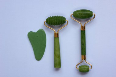 Mavi arka planda izole edilmiş iki kuvars yeşim taşı ve Gua sha taşı. Cilt bakımı yüz masajı ve rahatlama konsepti. Düz yat, boşluğu kopyala.