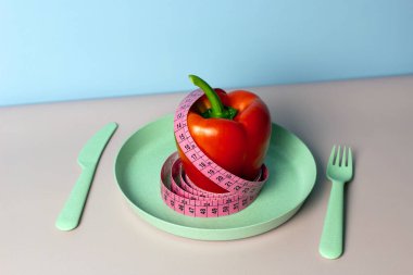 Tabakta çatal ve bıçakla mezura bulunan dolma biberli modaya uygun bir düzen. Aralıklı, keto, detoks ve ince diyetler. Sağlıklı beslenme konsepti. Düz yat, boşluğu kopyala.