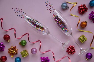 Pembe arka planda gözlük ve şenlik dekorasyonları olan modaya uygun bir yer. Yılbaşı ve parti konseptlerini kutlamak. Tebrik kartı. Düz arkaplan.