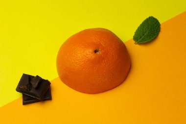 Parlak bir arka planda turuncu, çikolata ve nane karışımı. Meyve aromalı karışım. Yaratıcı minimalizm kavramı. Boşluğu kopyala.