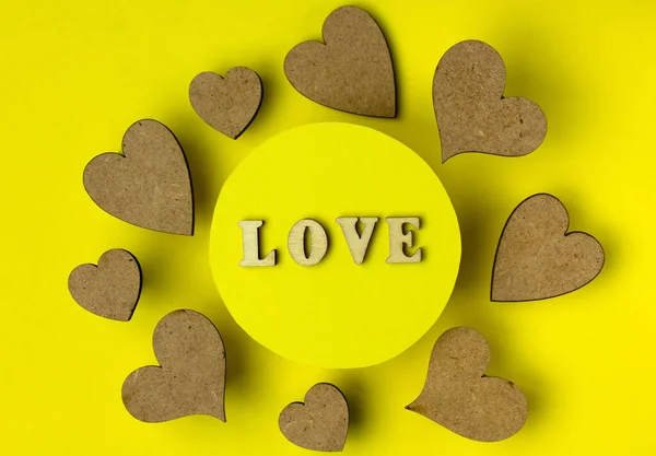 Hearts and word love made from wooden letters. Yellow background. The concept of holidays and love.  Flat lay, copy space.