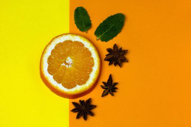 Yaratıcı düz kompozisyon, bir dilim portakal, yıldız anason, parlak bir arka planda nane. Meyve aromalı karışım. Minimalizm kavramı. Boşluğu kopyala.