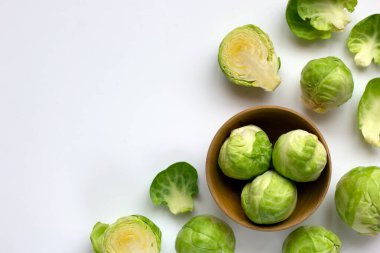 Yeşil brussel lahanası ve beyaz arka planda ahşap plaka modayı. Sağlıklı ve vejetaryen gıda malzemeleri. Kopyalama alanı ile yaratıcı kavram.