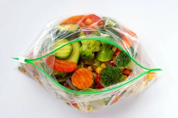 Beyaz arka planda plastik poşetlerde farklı organik donmuş sebzeler. Sağlıklı gıda depolama konsepti. Düz yatıyordu.