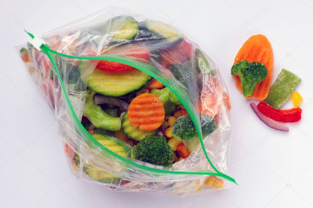 Set of different organic frozen vegetables in plastic bags on white background. Healthy food storage concept. Flat lay.
