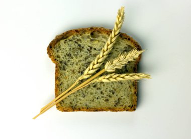 Lezzetli ekmek. Keten tohumlu bir parça ekmek, buğday taneli kulak ya da sivri uçlu bitki. Çavdar fırını beyaz arka planda izole edilmiş. Düz yat, boşluğu kopyala.