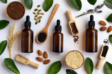 Düşürme şişesi maketi ve yeşil yapraklarla dekore edilmiş beyaz arka planda yüz yağı için malzemeler. Bitkisel kozmetik ürünleri, doğal organik kozmetik ürünleri, temel yağ paketleme tasarımları..