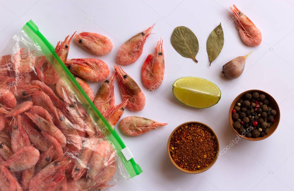 Seafood with lime, garlic and spices. Frozen raw shrimps. Healthy food preparation, cooking, diet, nutrition concept. Top view, copy space.