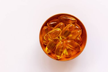 Beyaz arka planda küçük bir tabakta sarı haplar ya da tabletler. Sağlık konsepti. Düz yat, boşluğu kopyala.