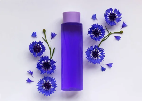 Beyaz arka planda şişe ve çiçek desenli modaya uygun bir kompozisyon. Doğal kozmetik spa konsepti. Organik kozmetik ürünleriyle soyut podyum. 