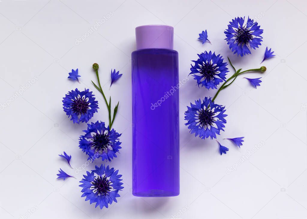 Trendy composition with bottle and cornflower flowers on a white background. Natural cosmetic spa concept. Abstract podium with organic cosmetic products. 