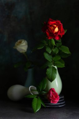 Koyu arkaplanlı vazolarda güller olan modaya uygun bir kompozisyon. Yaratıcı hala hayat konsepti. Boşluğu kopyala.