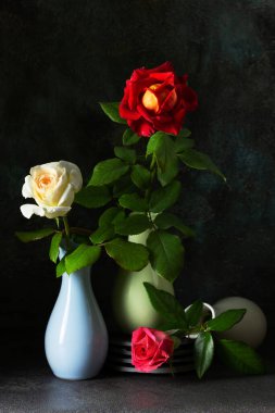 Karanlık arka planda güller olan yaratıcı natürmort hayat. Moda kompozisyon konsepti. Boşluğu kopyala. 