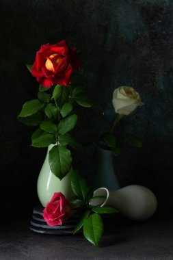 Koyu arkaplanlı vazolarda güller olan modaya uygun bir kompozisyon. Yaratıcı hala hayat konsepti. Boşluğu kopyala. 