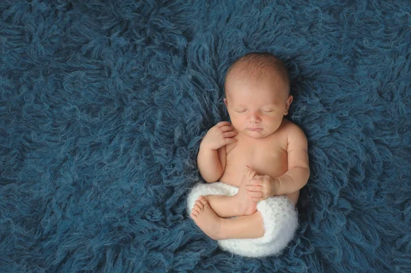 Nyfödd Baby Boy sova på en mörk blå Flokati matta — Stockfoto