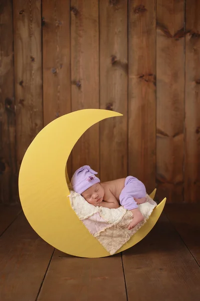 Menina recém-nascida dormindo na lua — Fotografia de Stock