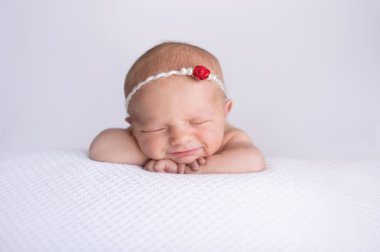 Smiling Newborn Baby Girl Wearing a Red Rose Headband clipart