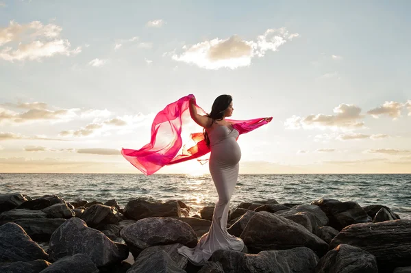 Mulher grávida na praia com véu rosa — Fotografia de Stock