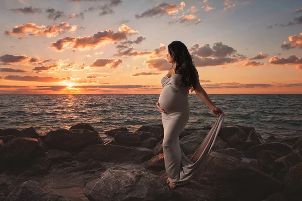Vackra gravid kvinna på stranden vid soluppgång — Stockfoto
