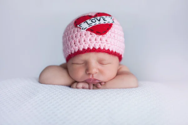 Menina recém-nascida vestindo um chapéu de "amor" — Fotografia de Stock